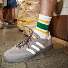 Load image into Gallery viewer, Person wearing a gray Adidas sneaker with white stripes on a sidewalk.

