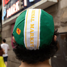 Load image into Gallery viewer, A green Cycling Cap with a white vertical stripe and yellow lettering reading 'ORIGINAL MARKET' worn by a person in a real-world outdoor setting.
