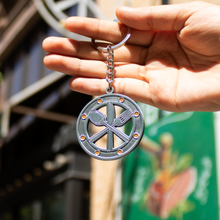Load image into Gallery viewer, Hand holding a keychain with a circular design featuring a spoon, fork, and knife.
